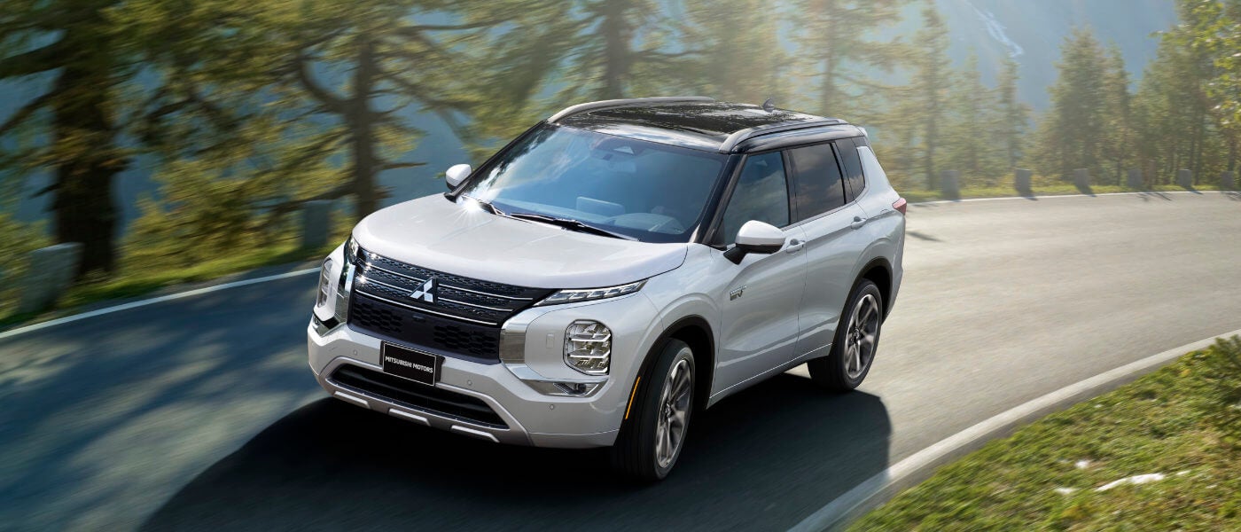 2024 Mitsubishi Outlander PHEV turning on sunny forest road
